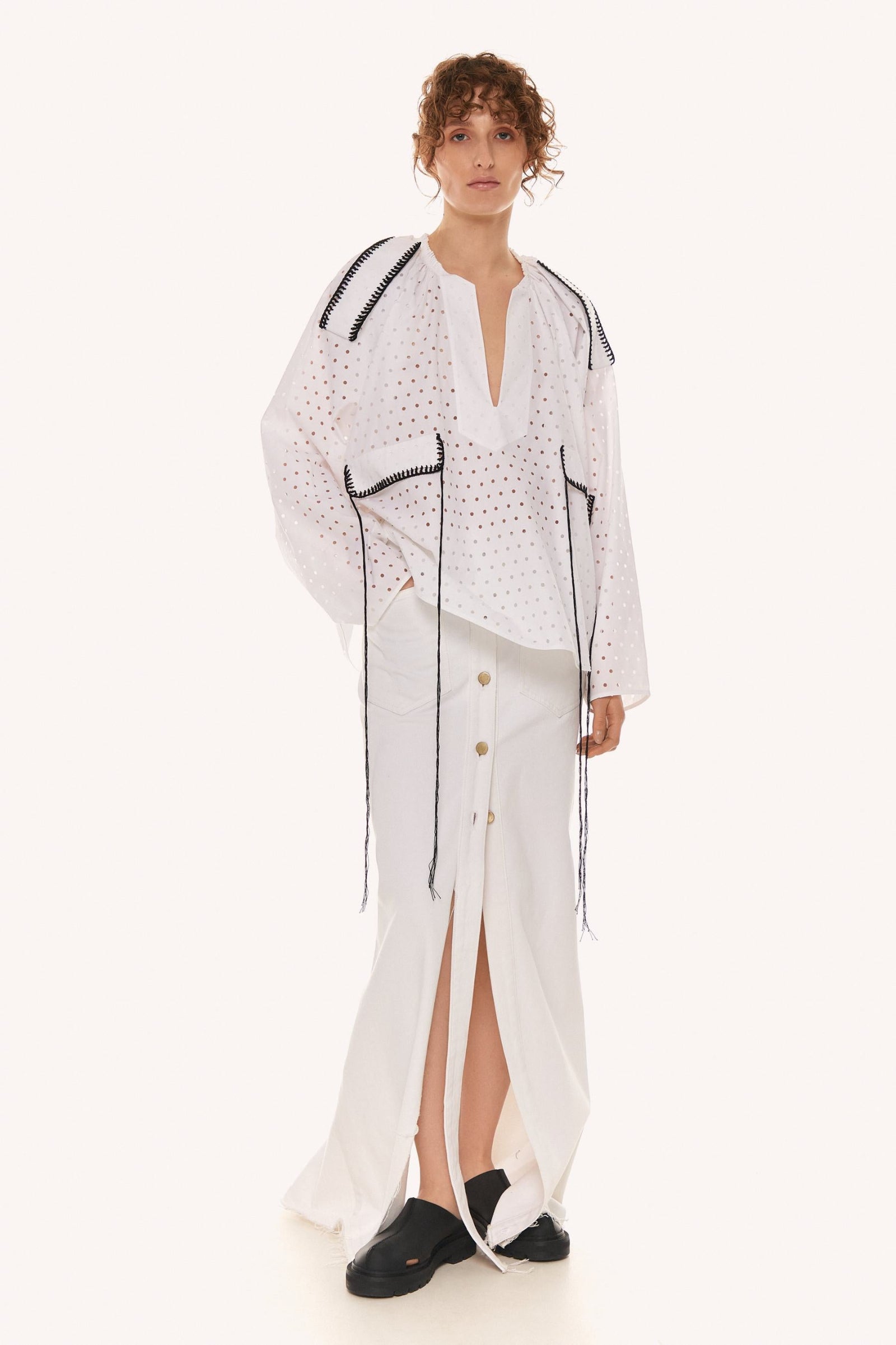 This image features a stylish white Oberih shirt, characterized by its unique design elements and target-like patterns. The WHITE OBERIH SHIRT is crafted from 100% cotton, providing a comfortable base, and is detailed with 100% linen for added texture and breathability.