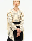 A model wearing a beige and black striped corset top SVITA CORSET with long fringe detailing, paired with black trousers.