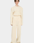 A model wearing loose-cut beige pants with an elastic waistband SOUL PANTS IVORY.