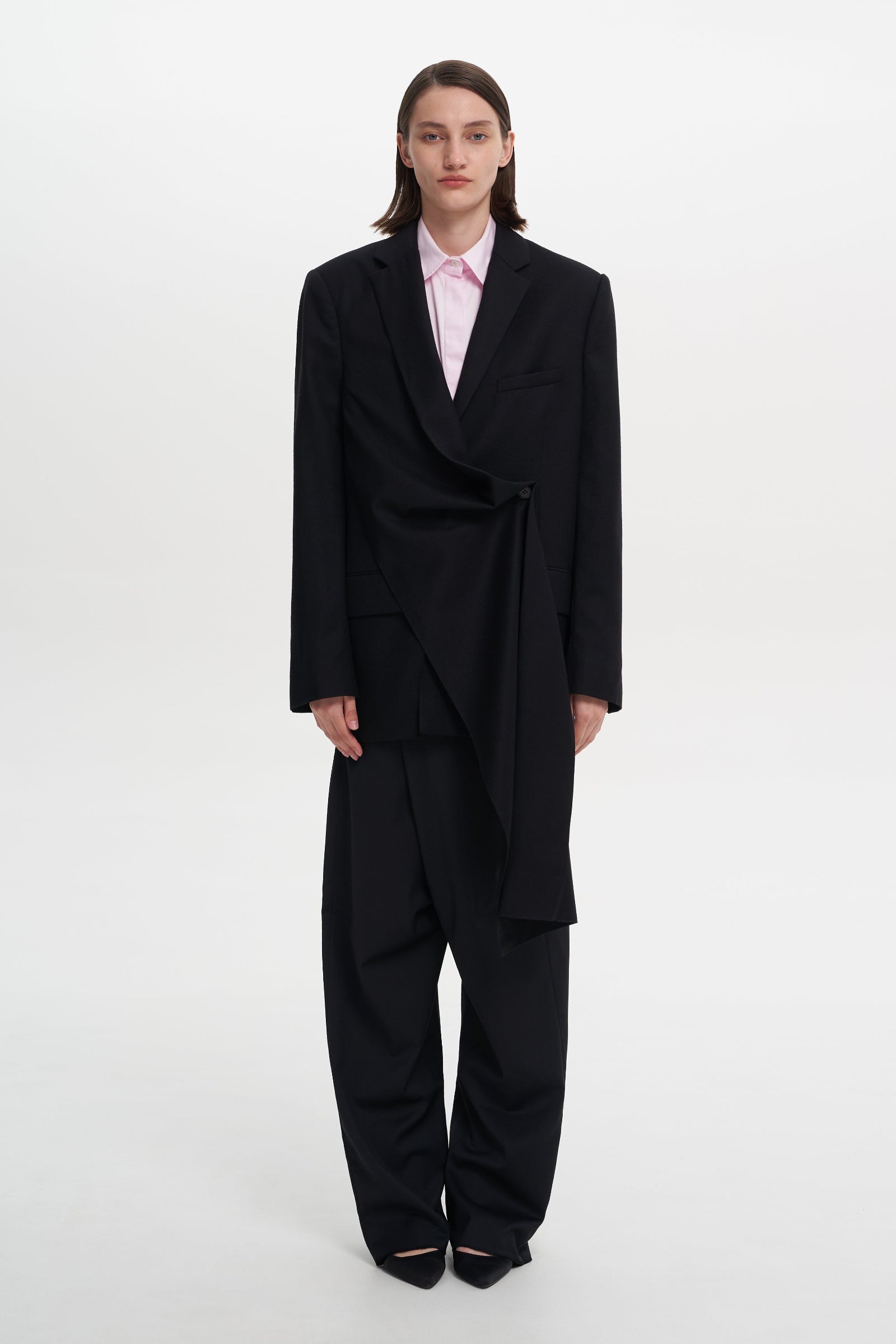 A model wearing a black, asymmetrically designed jacket TAG JACKET with a mandarin collar and long sleeves.
