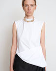 A woman wearing a white sleeveless cotton shirt with a twisted design at the waist, paired with a black skirt and a necklace. WAIST TWISTED COTTON SHIRT 