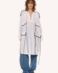 This image features a minimalist white dress with distinctive black detailing, presenting a modern and elegant aesthetic. The WHITE OBERIH DRESS dress is crafted from 100% cotton, highlighting both comfort and sustainability.
